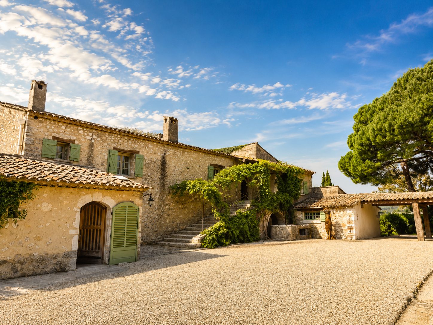 Stone facade of the main farmhouse at Mas des Serres, with green shutters